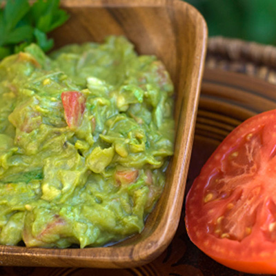 Tomato baskets stuffed with guacamole, on a cucumber nest